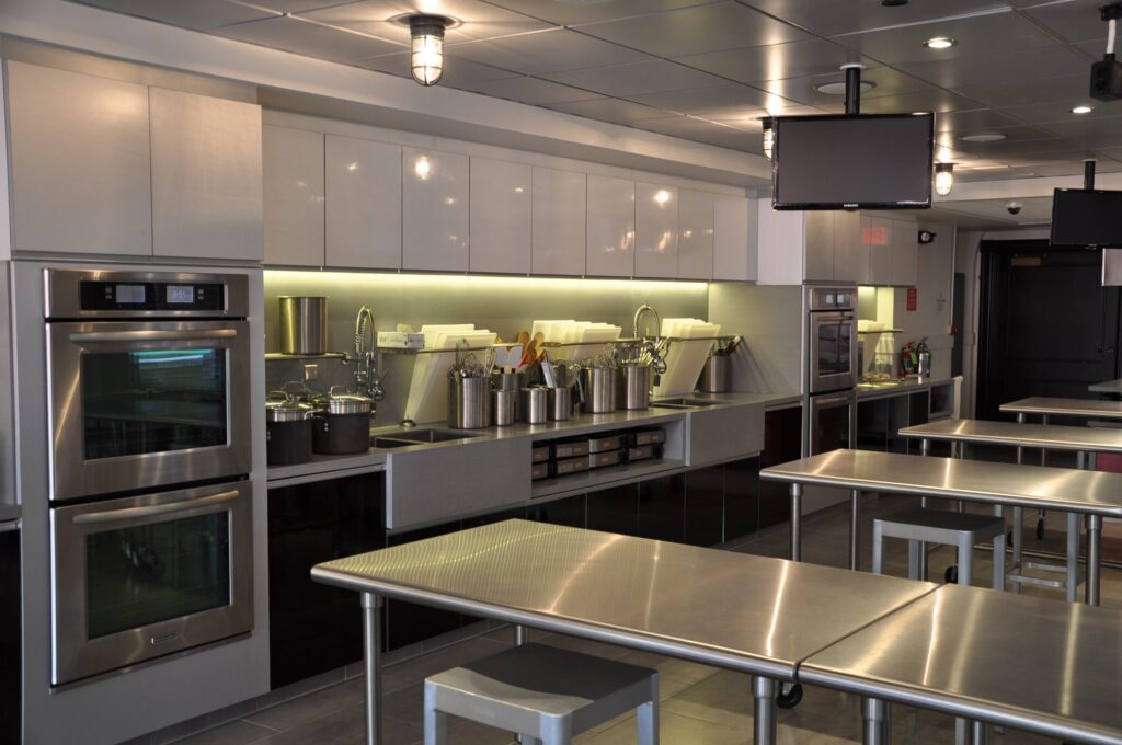 Modern cafeteria with food display counter and a chef at work in the kitchen area.