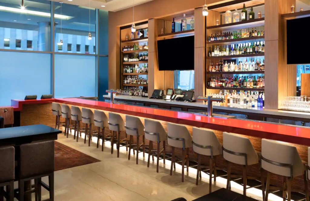 Modern cafeteria with food display counter and a chef at work in the kitchen area.