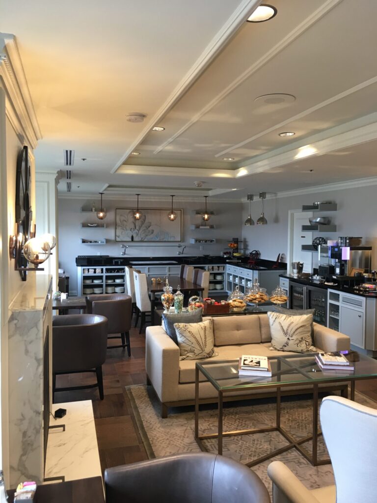 Modern cafeteria with food display counter and a chef at work in the kitchen area.