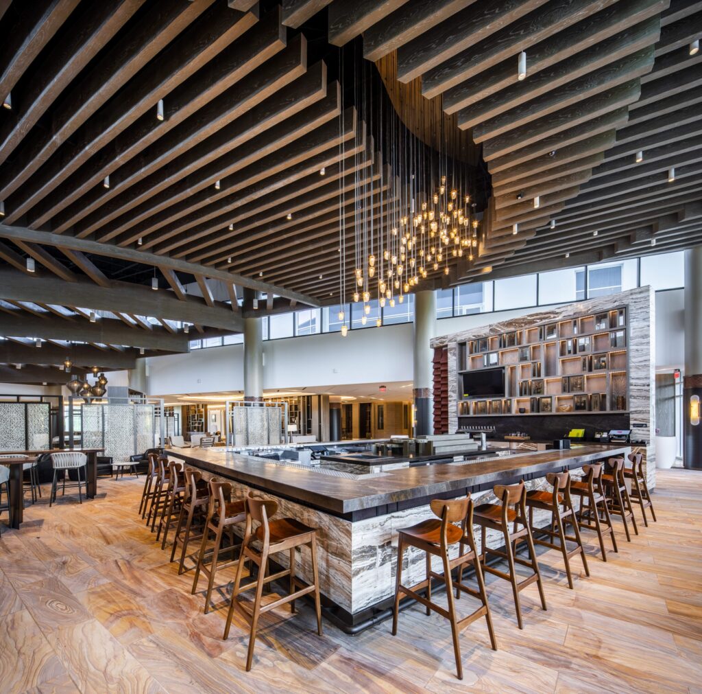 Modern cafeteria with food display counter and a chef at work in the kitchen area.