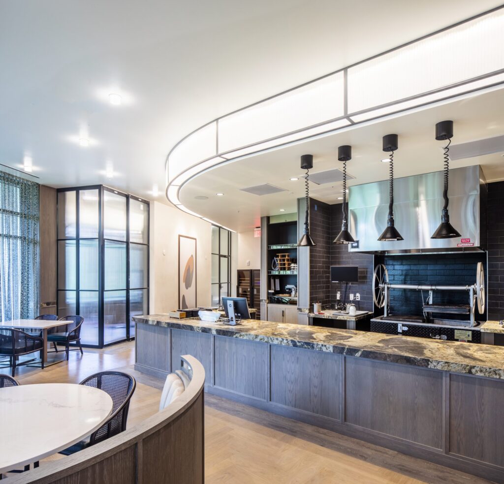 Modern cafeteria with food display counter and a chef at work in the kitchen area.