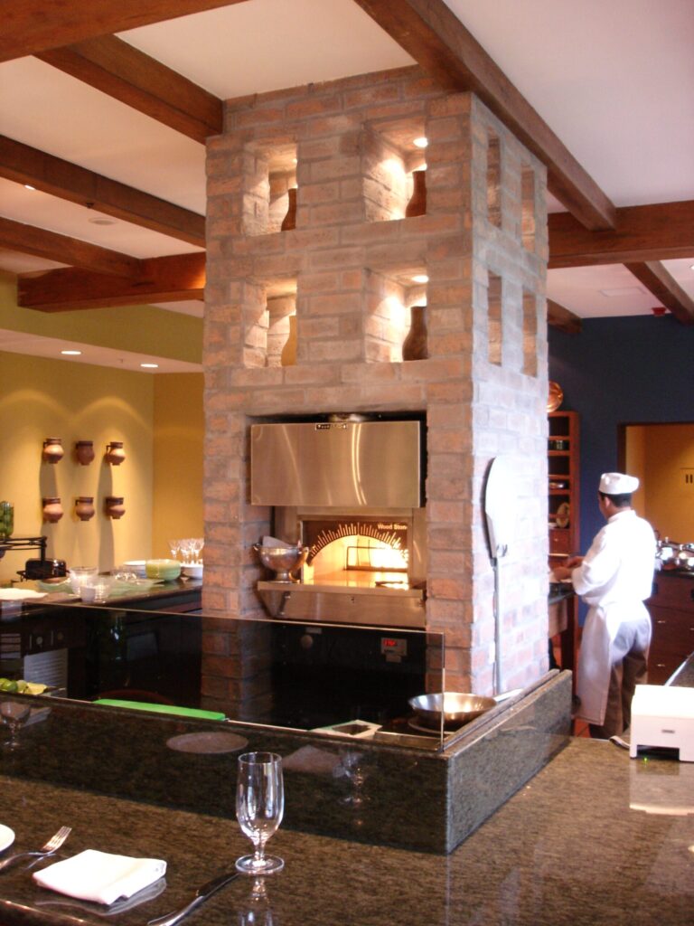 Modern cafeteria with food display counter and a chef at work in the kitchen area.